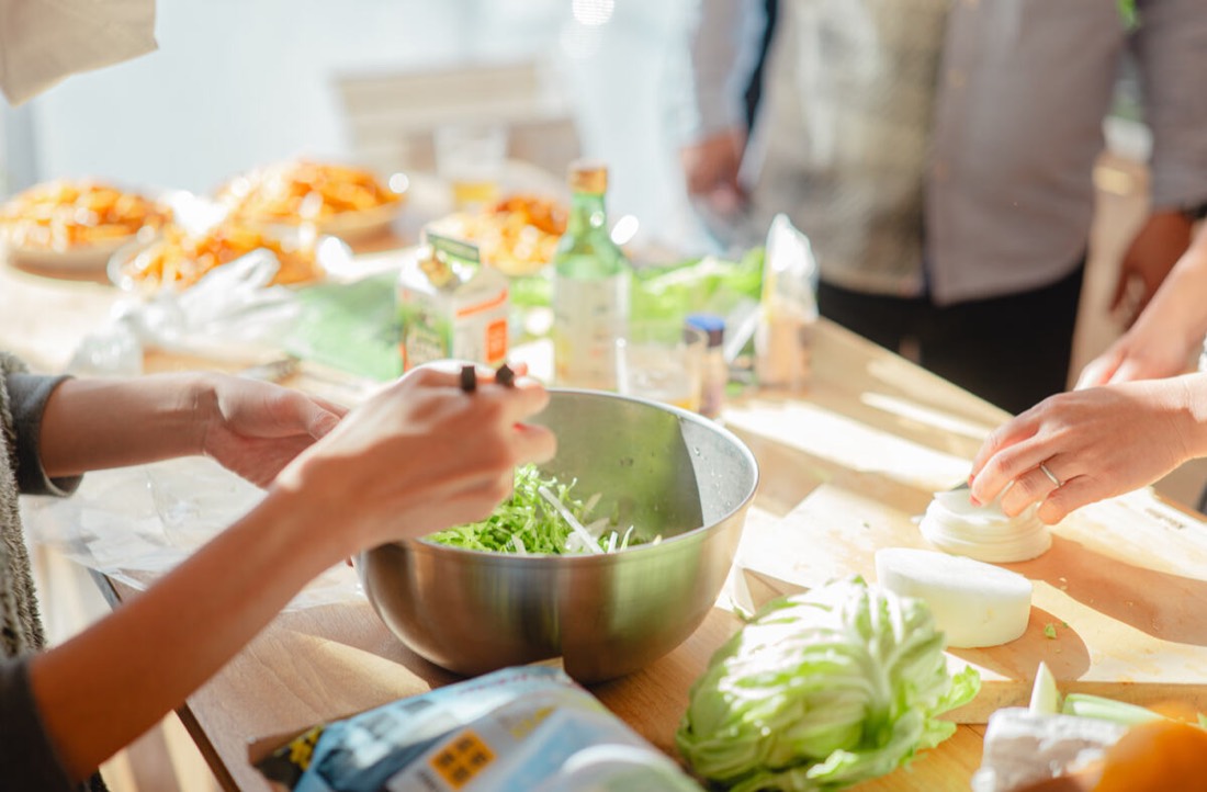 Hands preparing a salad together
